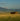 Wooden cabin in a field with mountains in the background