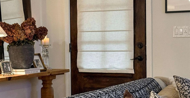 A custom white Roman shade fitted to the glass area of a dark wood French door