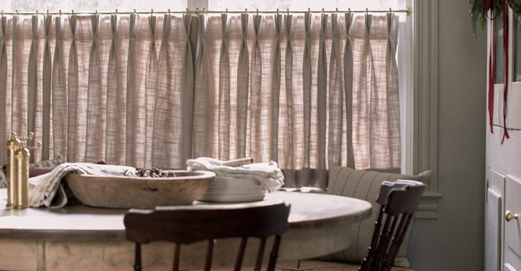 Light gray cafe curtains on a bright kitchen window