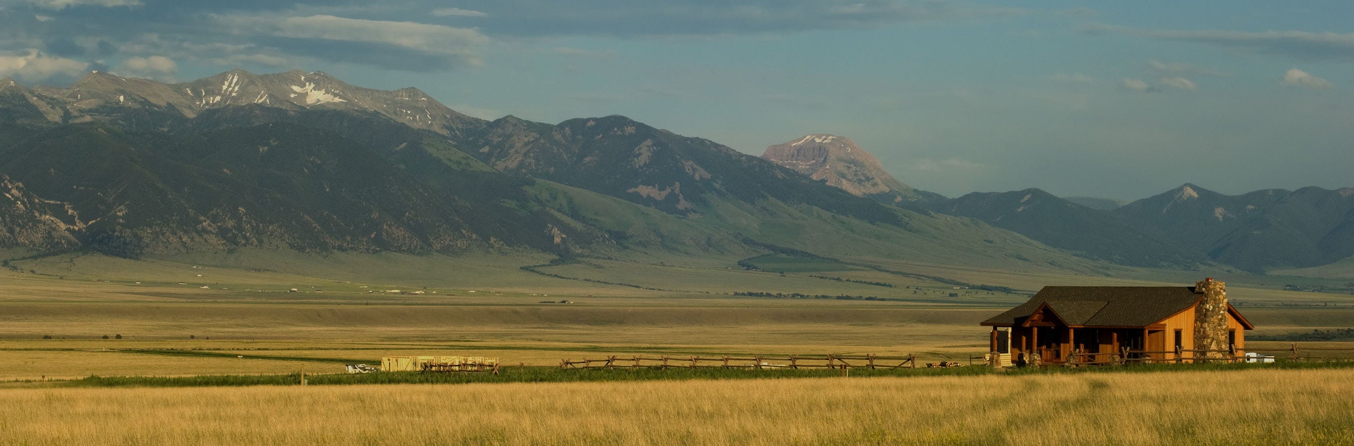 Remote cabin in a field with mountains in the background