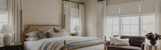 Neutral bedroom with floor-length custom curtains and Roman shades filtering soft natural light