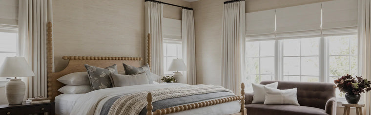 Neutral bedroom with floor-length custom curtains and Roman shades filtering soft natural light
