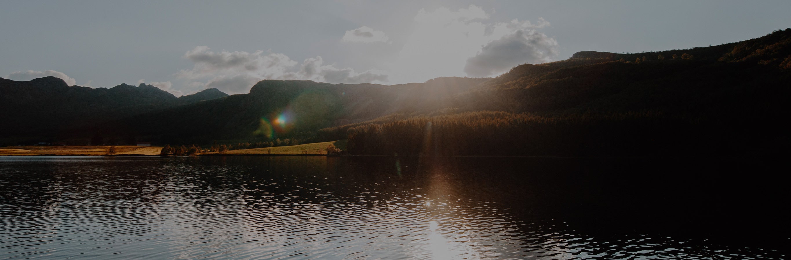 The sun setting over a tranquil lake and mountains symbolizes the restorative calm Alfred Stripe Linen Custom Curtains bring, with natural materials and effective light-blocking for a peaceful sanctuary.