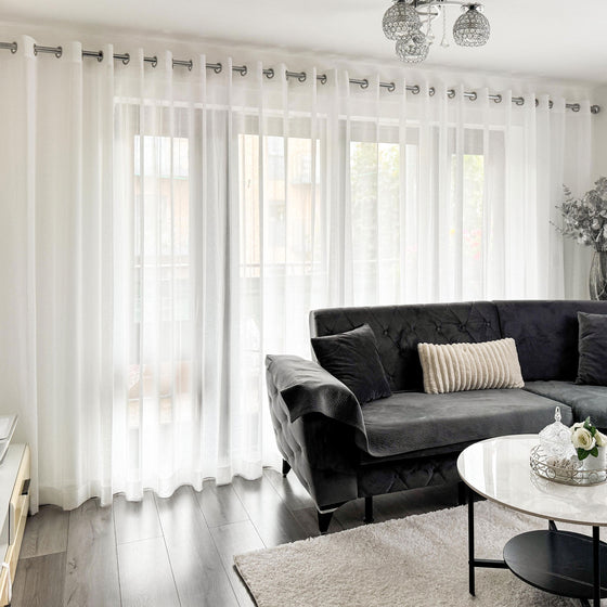 White,Living room with gray sofa, white curtains, and a coffee table.