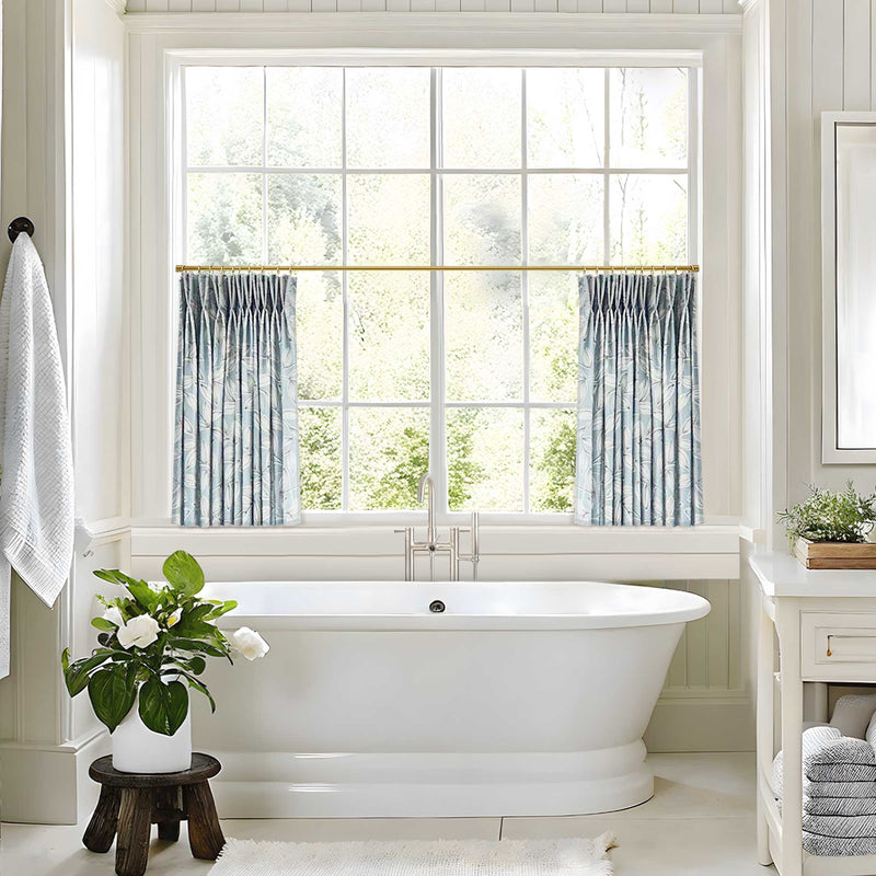 Bathroom with a freestanding bathtub, window, curtarra fronde blue cafe curtains and decorative elements.
