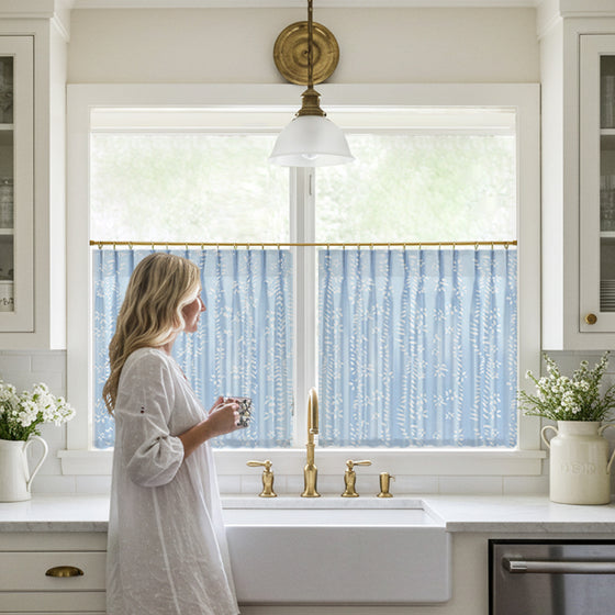 Blue designer pattern cafe curtains hanging on a window, with an irregular dotted texture.