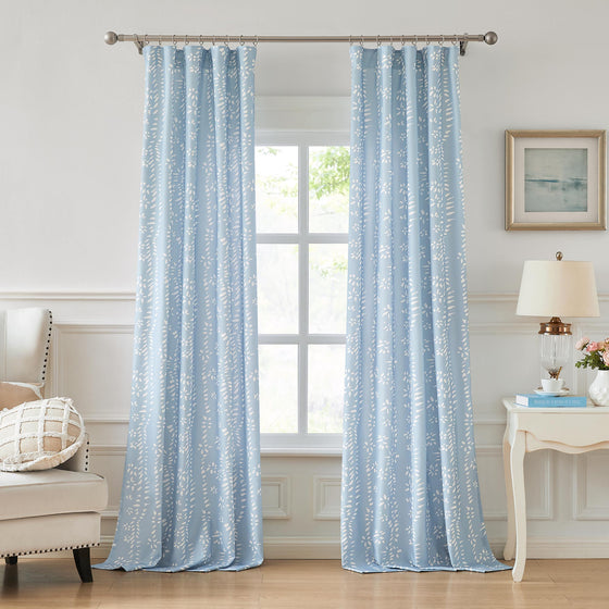 A living room scene with large windows showcasing blue designer pattern curtains with an irregular dotted texture. 